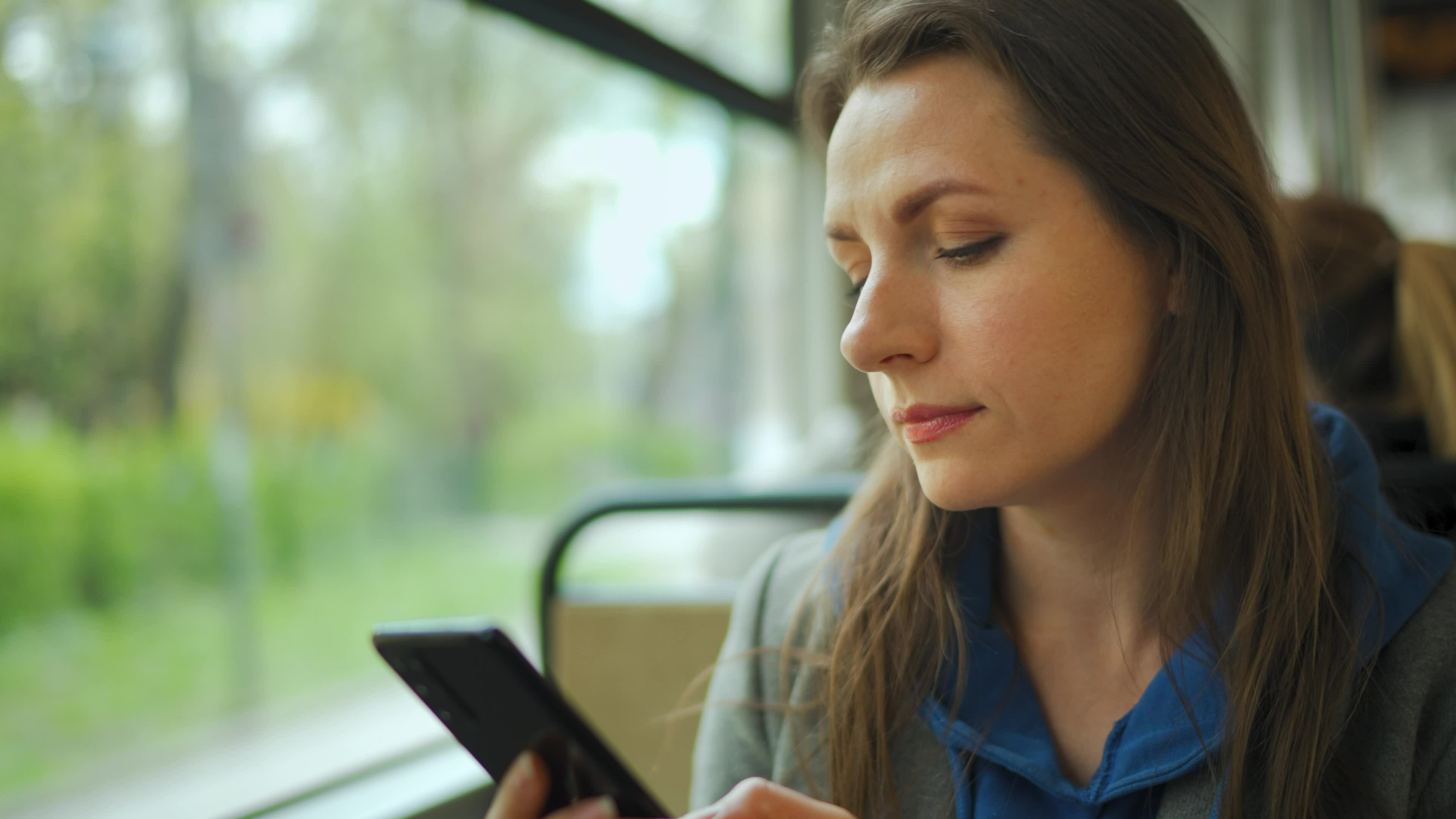 A woman using a smartphone while travelling on public transport.